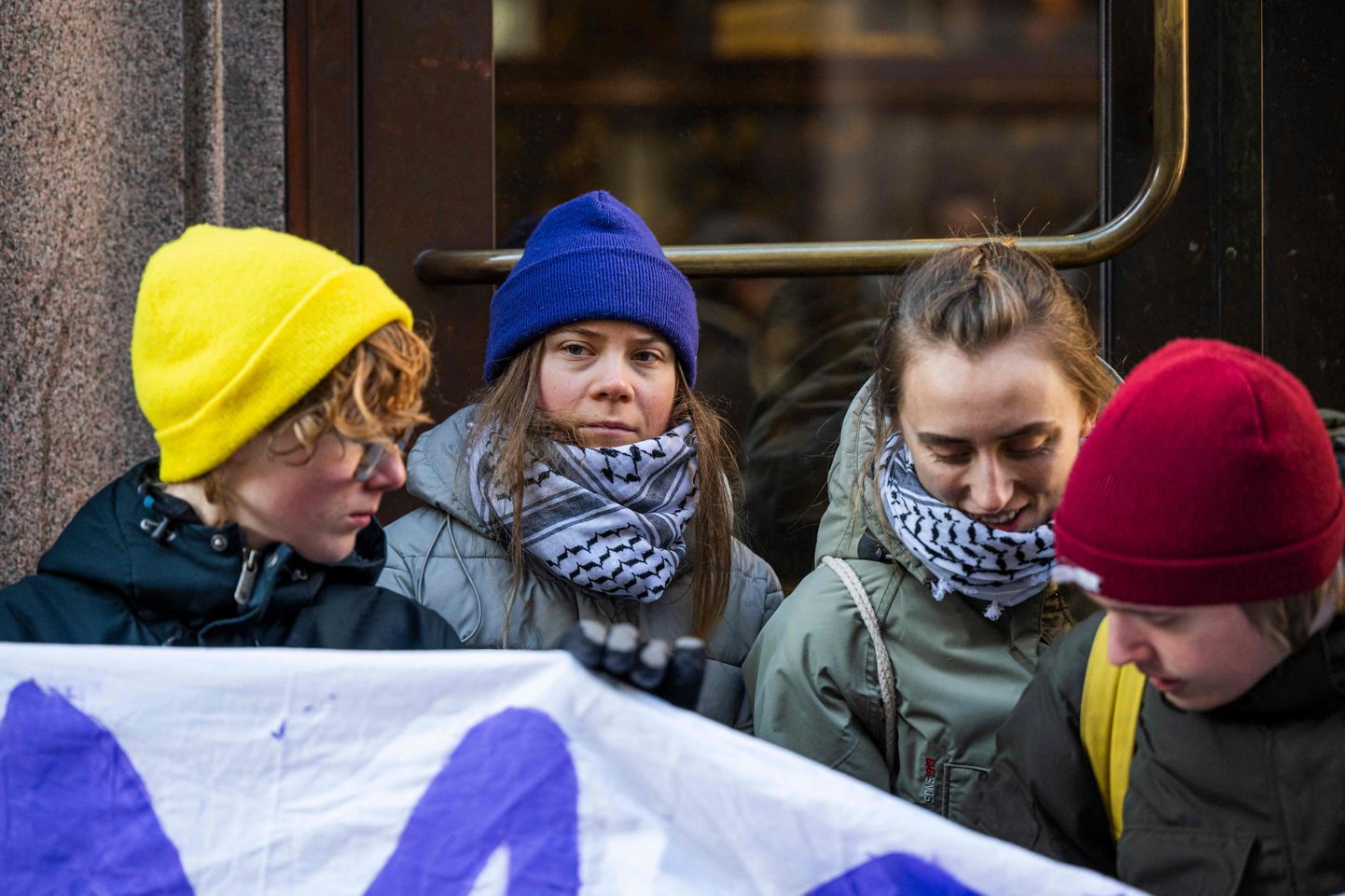 Kliimaaktivist Greta Thunberg (sinises mütsis) täna koos kaaslastega Stockholmis tõkestamas sissepääsu Rootsi parlamendi hoonesse.
