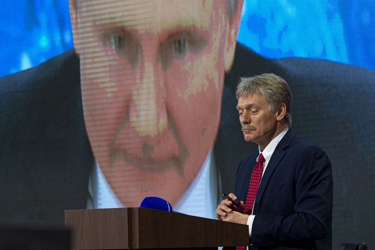 Дмитрий Песков на фоне изображения Владимира Путина