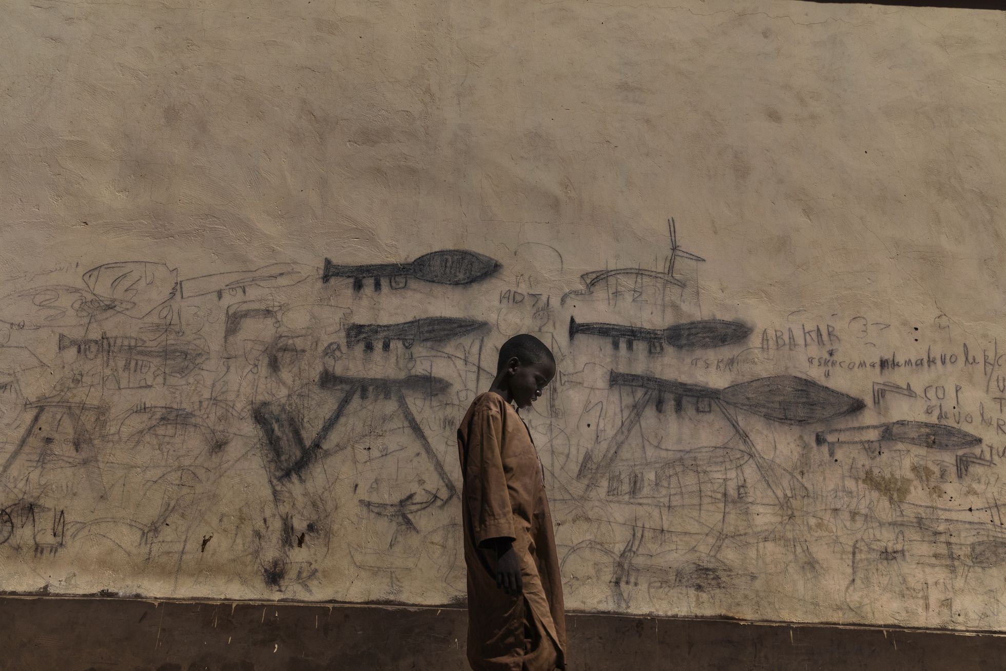 Orvuks jäänud poiss jalutab Tšaadis Boli linnas mööda seinast, kuhu on joonistatud raketiheitjad.