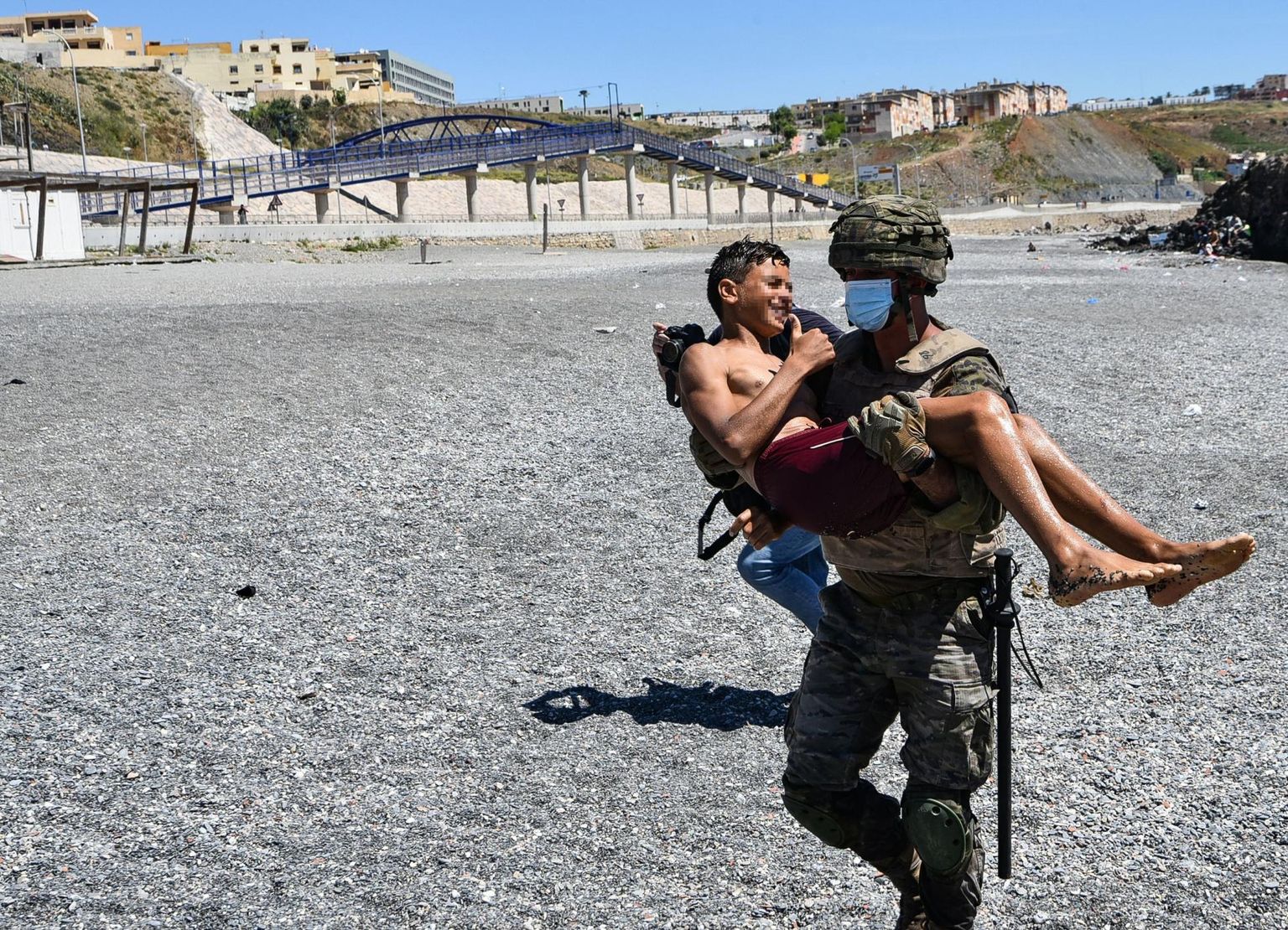 Hispaania sõdur kandmas maroko last Ceuta rannast ära.
