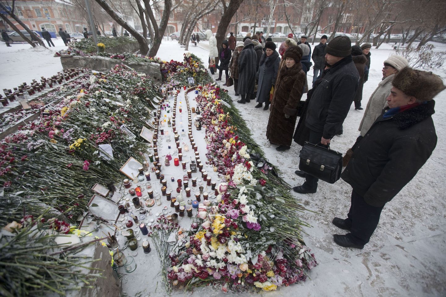 Inimesed tulekahjuohvrite mälestuseks toodud lillede ja küünalde juures Permis.