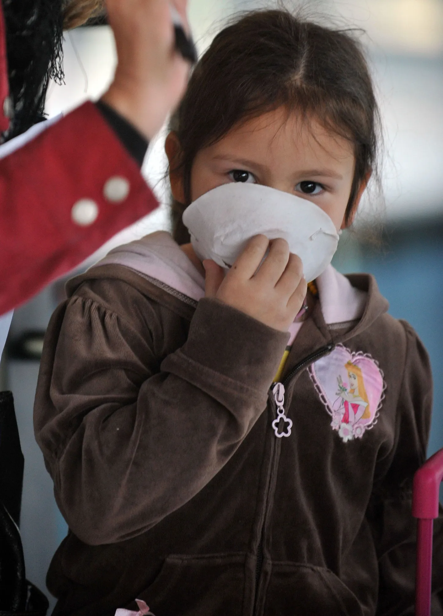 Mehhikost saabunud väike tüdruk varjub maski taha Tšiili pealinna Santiago rahvusvahelises lennujaamas.