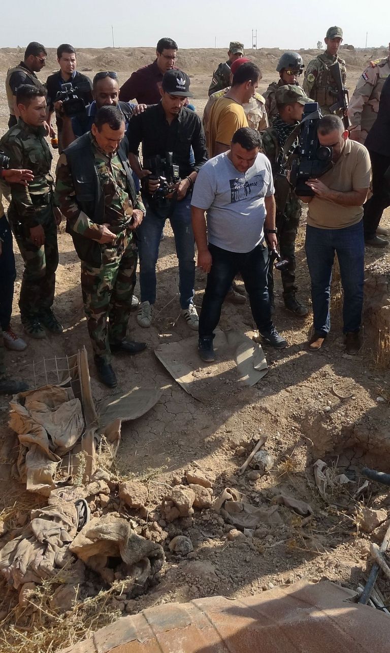 Iraagi väed ja ajakirjanikud massihauda uurimas.