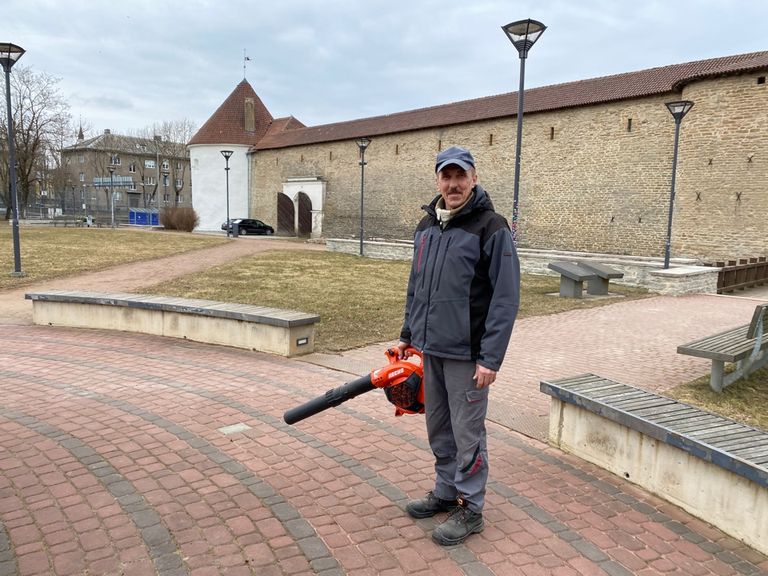 Рабочий Константин Заходяев воздуходувом очищает дорожки замкового парка
