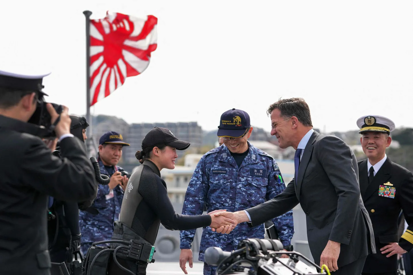 NATO peasekretär Mark Rutte surub kätt Jaapani naissõjaväelasel, kes kuulub lõhkeainete käitlemise üksusesse. Rutte külastas Jaapani mereliste enesekaitsejõudude baasi Kanagawa prefektuuris Yokosukas ja viibib antud fotol fregati FFM Mogami pardal.