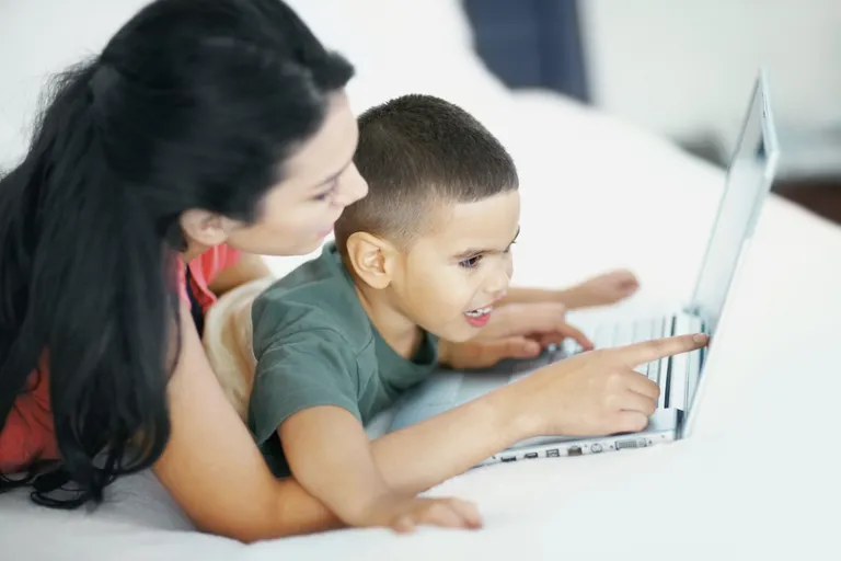 Naine õpetab last sülearvutit kasutama. / Scanpix