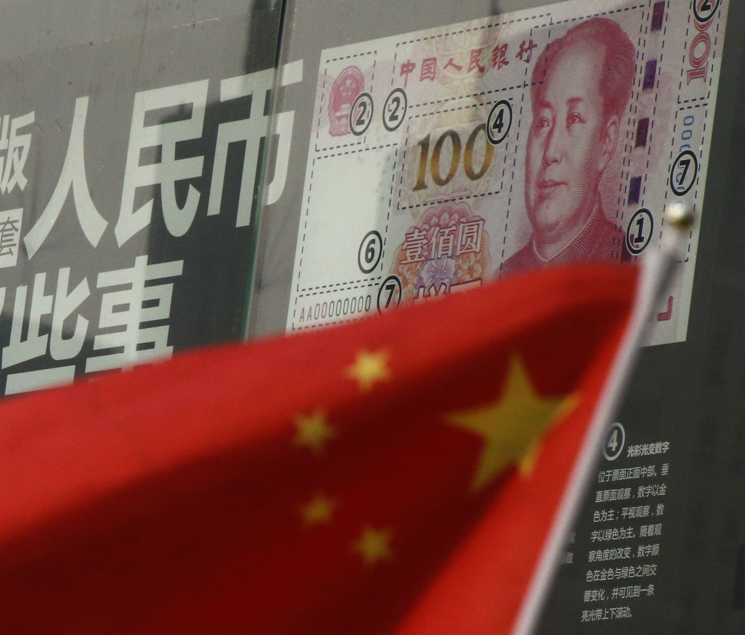 Hiina lipp uut sajajüaanist pangatähte tuvustava plakati taustal.