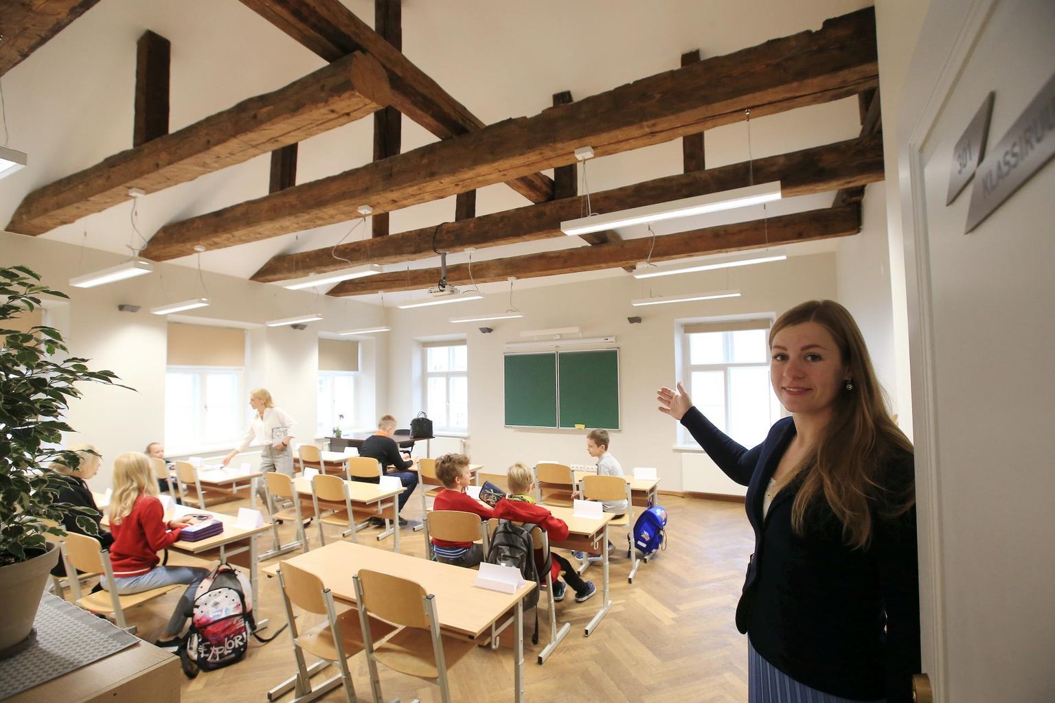 Kooli arendusjuht Maris Meus osutab viienda klassi uksel akende poole, millest avaneb vaade Tartu ülikooli peahoonele.