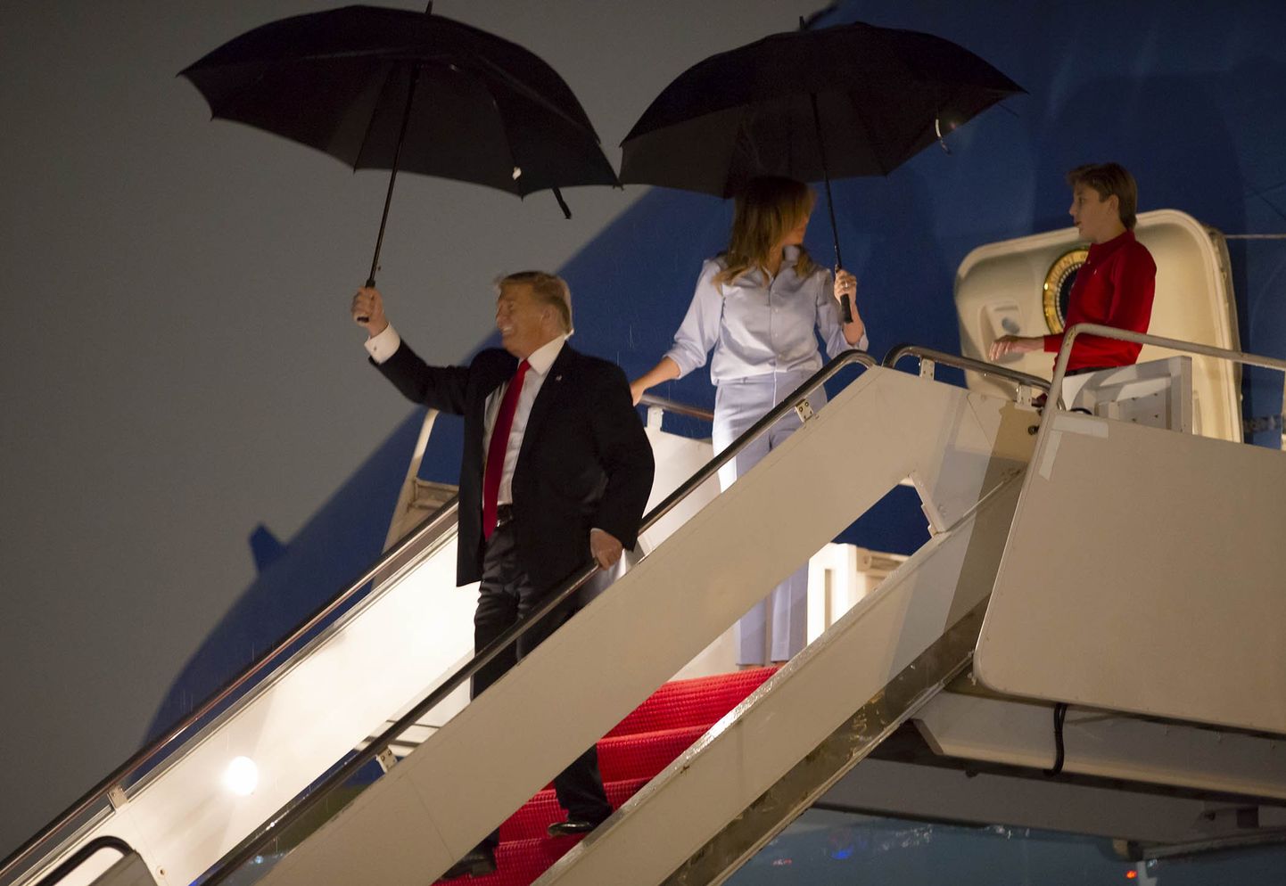 USA president DOnald Trump abikaasa ja pojaga eralennukist väljumas.