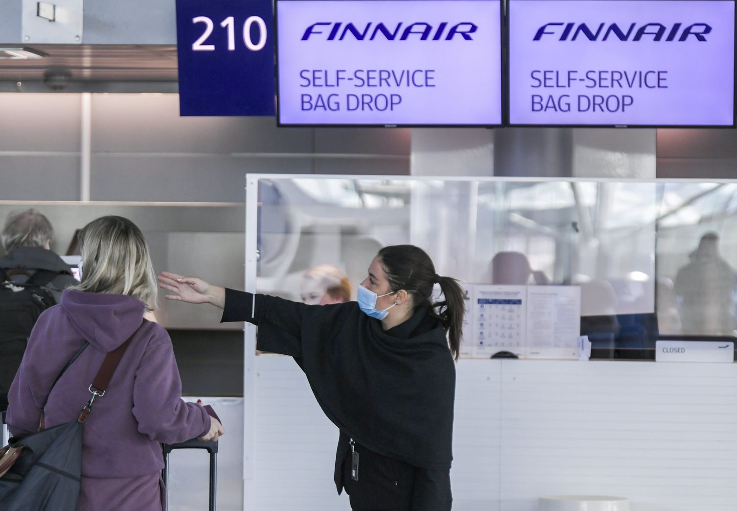 Soome lennufirma Finnair töötaja juhatamas Helsinki-Vantaa lennujaamas reisijat. Foto on tehtud 18. mail 2020