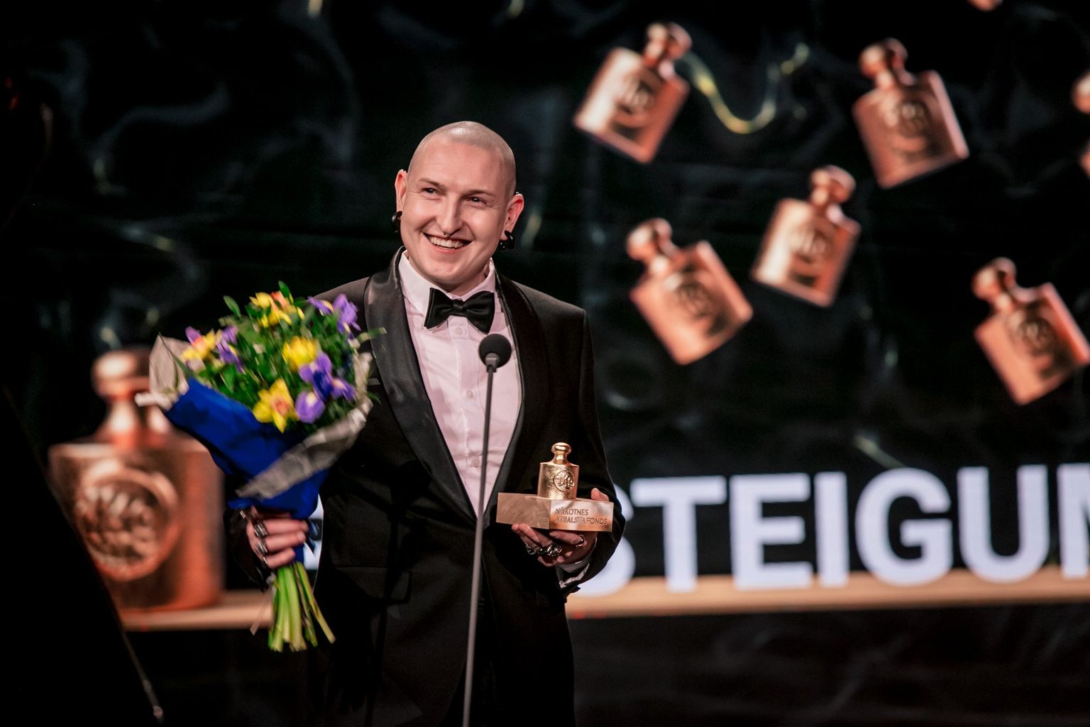 Mākslinieks Kristians Brekte, saņemot balvu 2022. gadā kategorijā "Pārsteigums" par sienas gleznojumu "Veltījums Džemmai Skulmei"