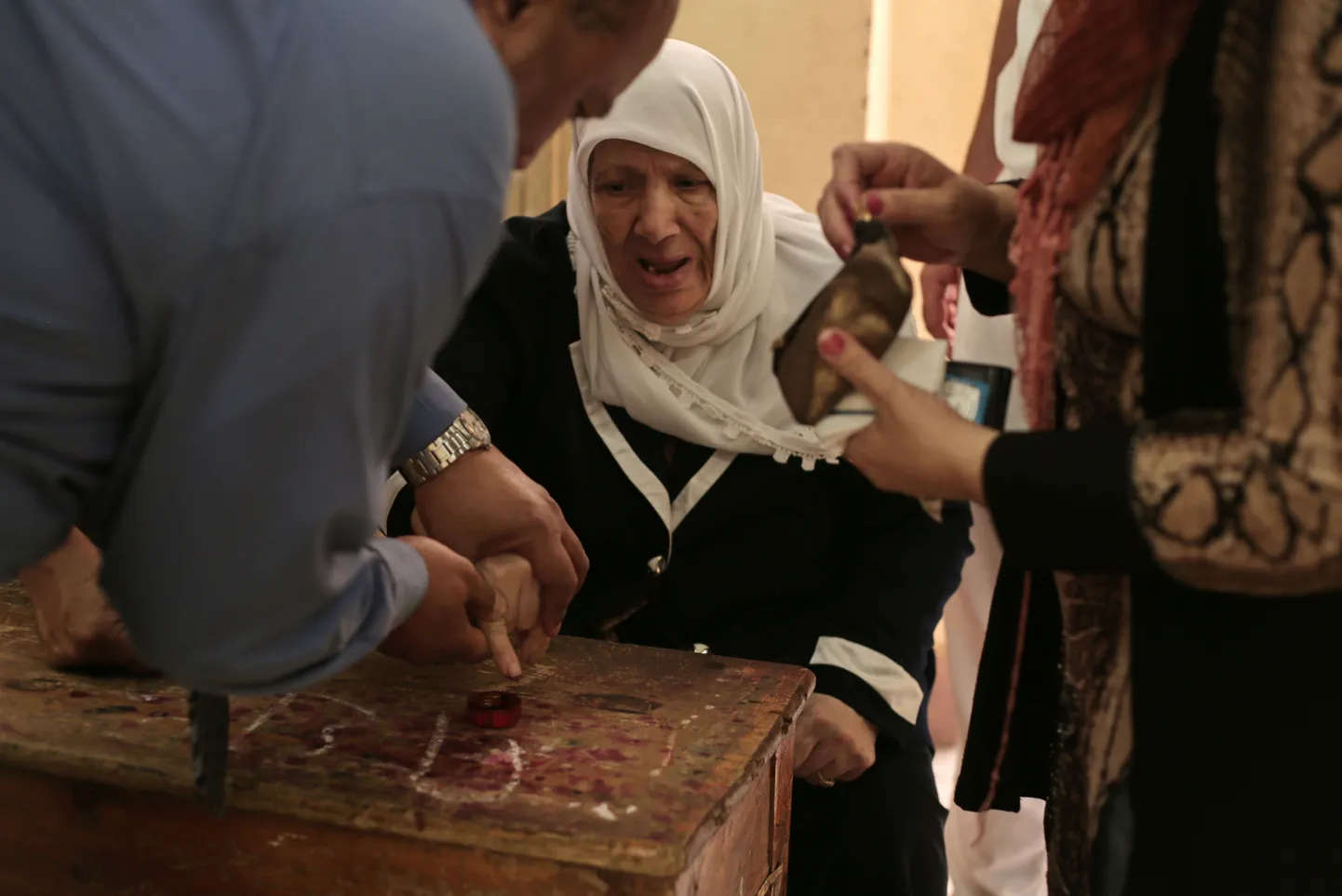 Сотрудник избирательной комиссии помогает проголосовать на президентских выборах пожилой египтянке.