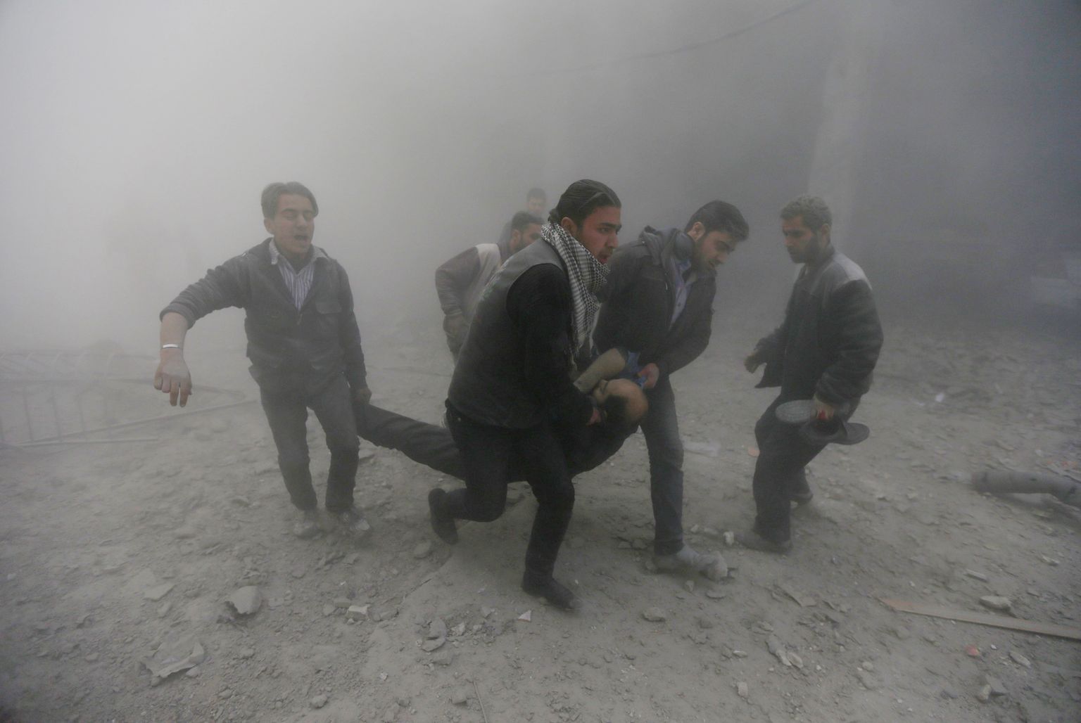 Süüria aktivistid valitsusvägede õhurünnaku ohvrit kandmas.