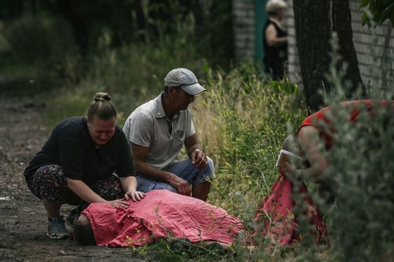 Жительница Лисичанска над телом члена семьи, убитого в результате обстрела, 18 июня 2022 года