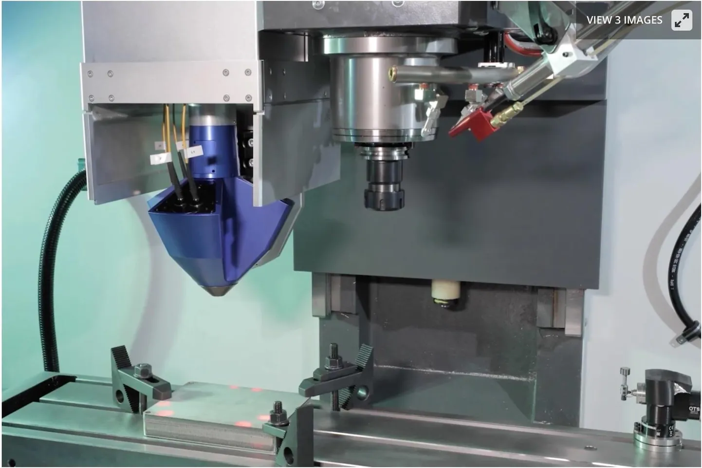 Laserpaagutades metallipuru 3D-printimiseks kasutav tööpea (vasakaul) arvutijuhtimisega koordinaatpinki paigaldatult. Paremal paikneb tööpingi enda spindel, millesse asetatakse lõiketerad printimisejärgseks viimistlemiseks.
