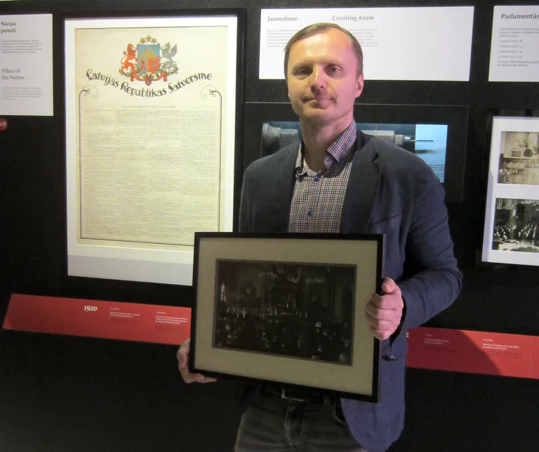 Fotogrāfijas dāvinātājs Egils Grasmanis pie Satversmes plakāta izstādē “Latvijas gadsimts”. 2020. gada 30. aprīlis