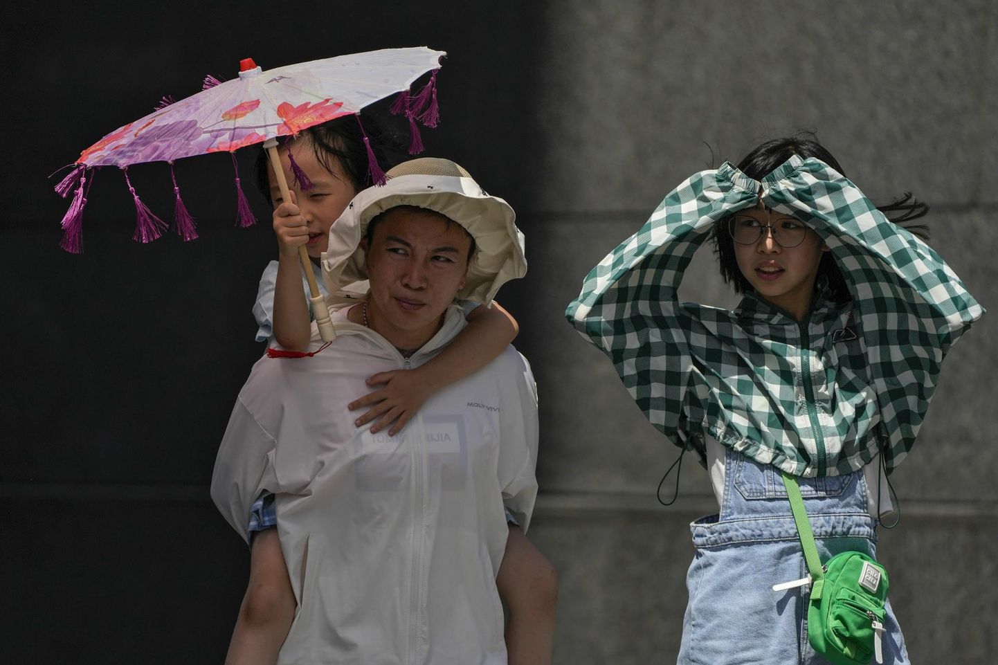 Pekingi perekond varjab end rõivaste ja varju abil lõõmava päikese eest praegu kestva kuumalaine ajal, mil temperatuurid küündivad 40 kraadi kanti.