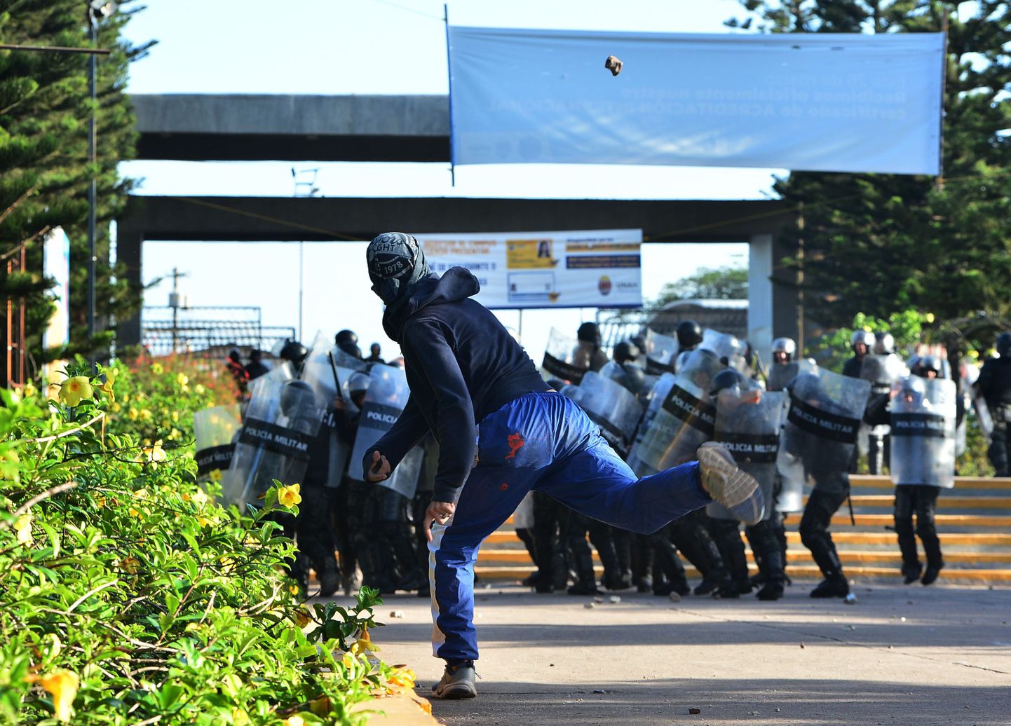 Õpilane Hondurase riiklikust autonoomsest ülikoolist viskab Hondurase sõjaväpolitseinike kiviga.