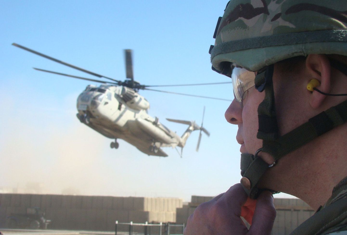 ISAFi koosseisu kuuluv Briti sõdur seab kiivrit paika. Tagaplaanil maandub NATO kopter tugibaasi Lashkar Gah's (Helmandi provints, Afganistan).