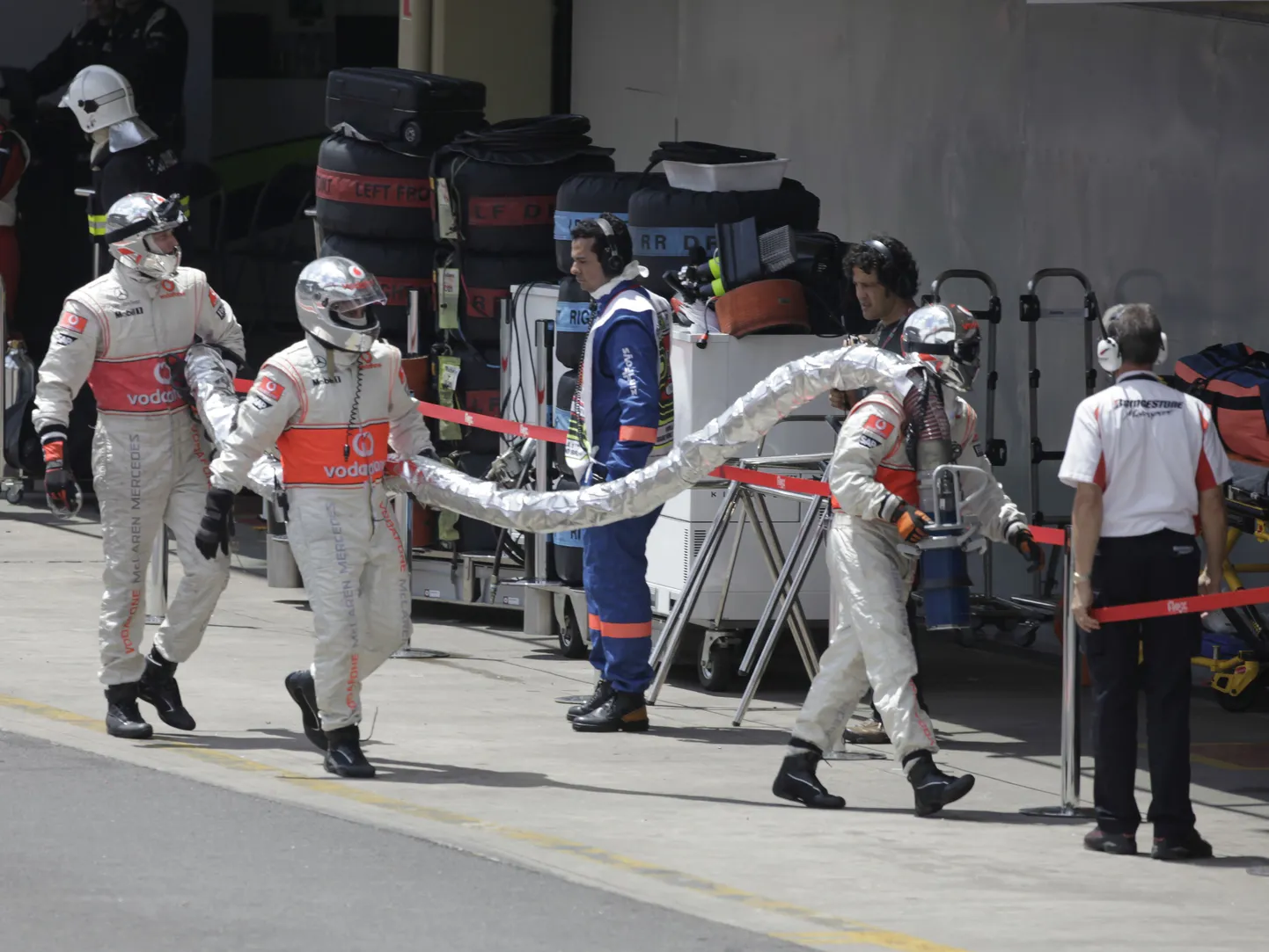McLareni meeskonna mehaanikud veavad Heikki Kovalaineni auto külge jäänud kütusevoolikut.