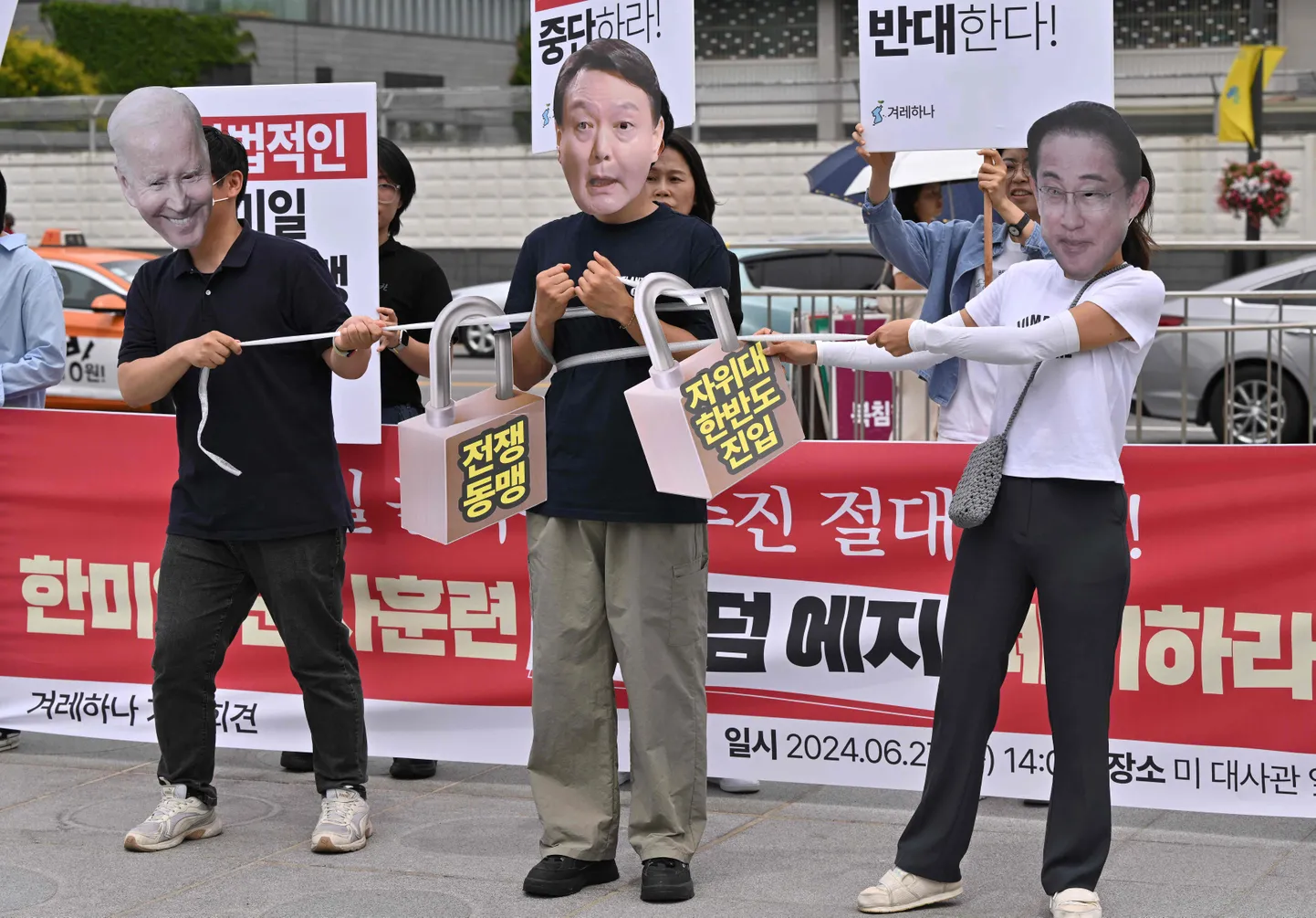 Sel 27. juunil tehtud fotol Soulis Ühendriikide suursaatkonna ees kannavad meeleavaldajad USA presidendi Joe Bideni, Lõuna-Korea riigipea Yoon Suk-yeoli ja Jaapani peaministri Fumio Kishida näoga maske ning protesteerivad papist tabalukkudega, millele on kirjutatud «sõjaliit», kolmepoolsete sõjaliste õppuste Freedom Edge vastu. Kolm lääneriiki korraldavad uusi mastaapseid ühisõppusi, teatas Souli ühendatud kindralstaap varem. Kolmiku eesmärk on seista jõuliselt vastu viimasel ajal üha sõjakamaks muutuvale Pyongyangile.