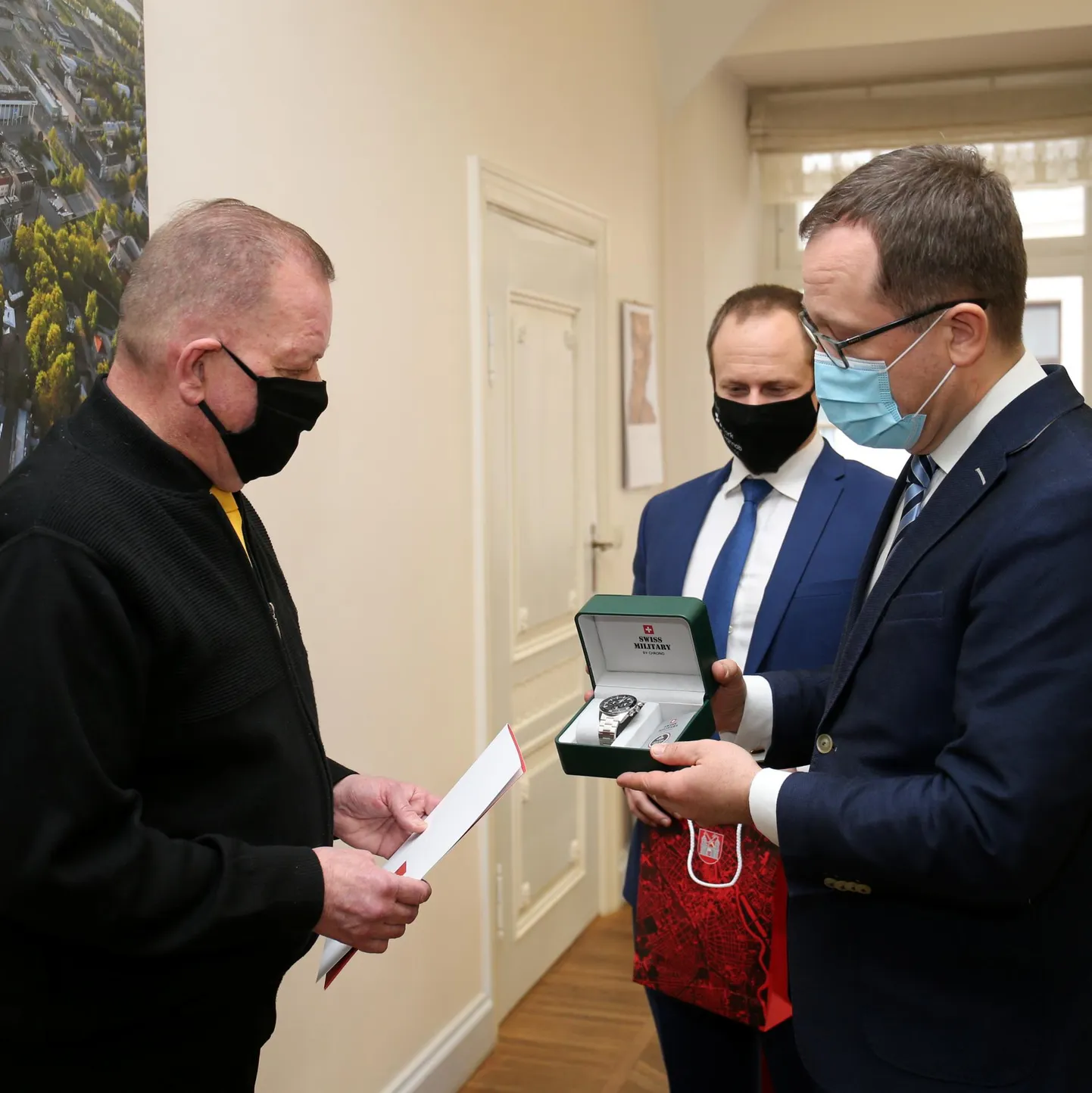 Tartu linnapea Urmas Klaas (paremal) tunnustab Skarabeus turvafirmas töötavat Aivar Volast (vasakul) uppuja päästmise eest kellaga. Tagaplaanil abilinnapea Mihkel Lees.