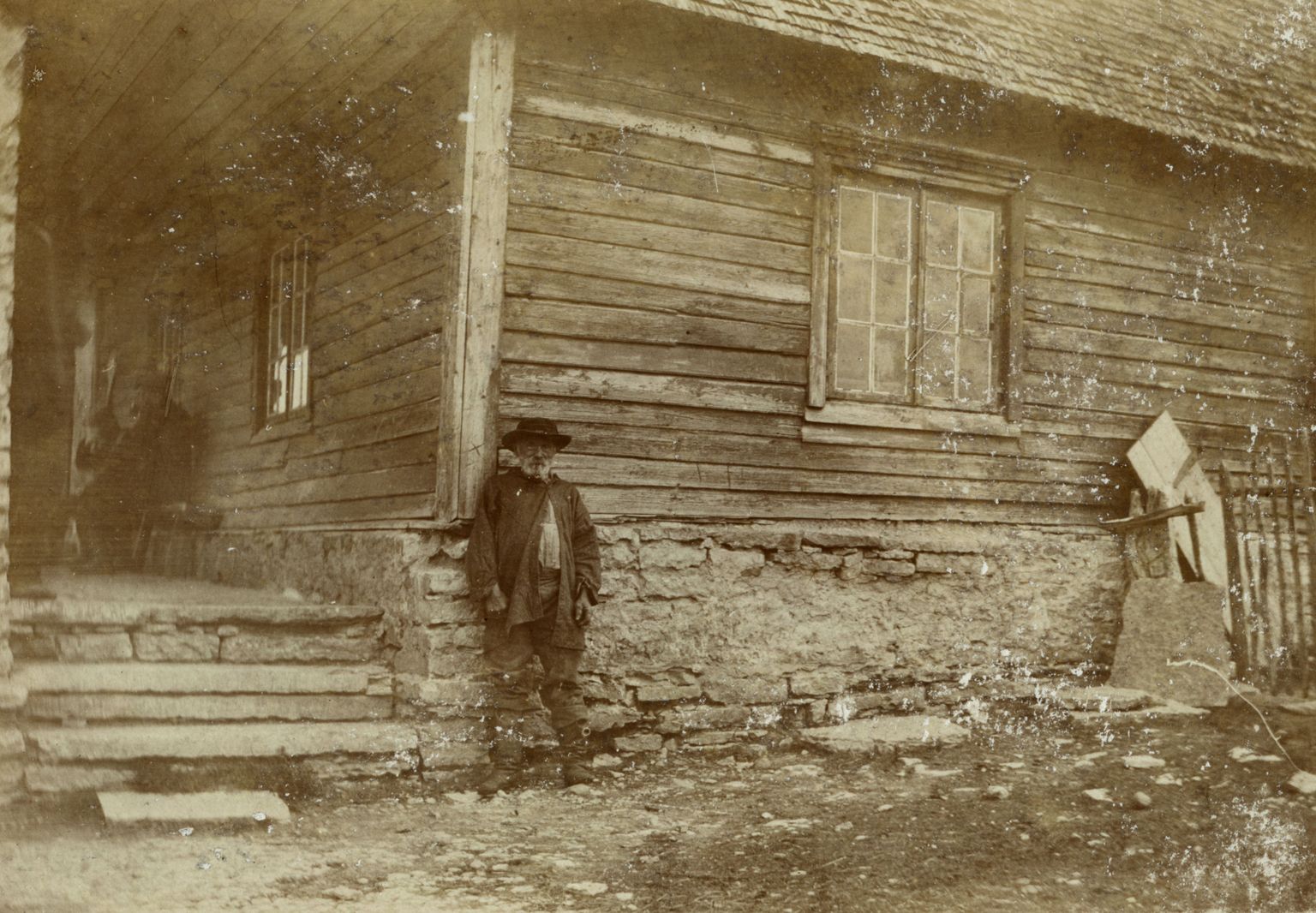 Pildil vana mees seismas Harku kõrtsi ees, umbes 1900.