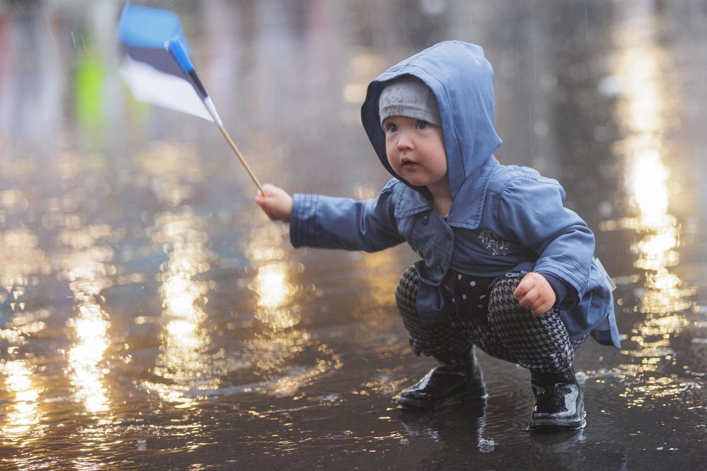Väike laps laulu- ja tantsupeol vihma nautimas.