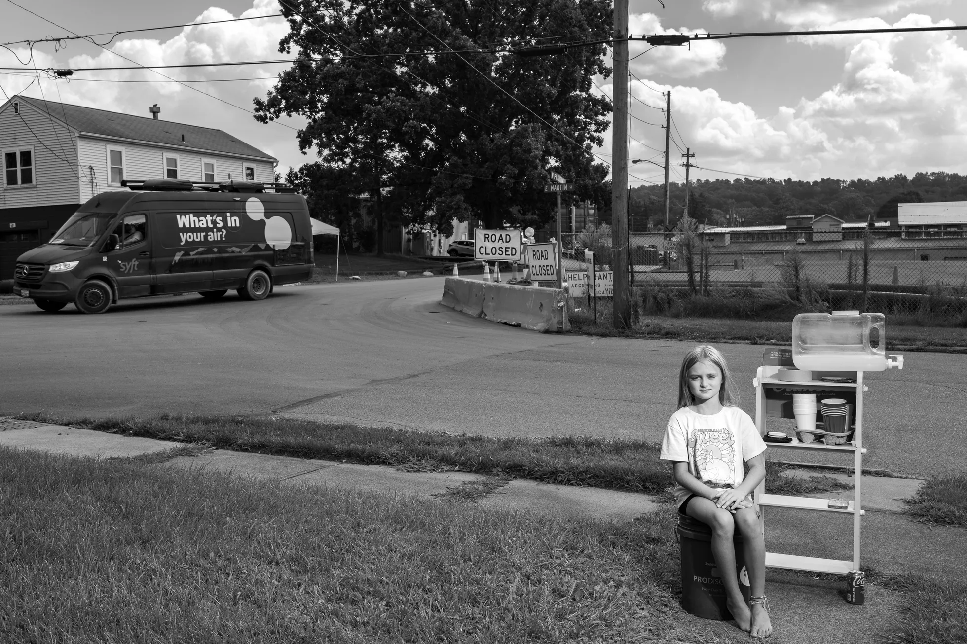 LaBrea Letson (8) müüb pudeliveest valmistatud limonaadi oma vanaema kodu ees rongiõnnetuse koha lähedal. Mööduv kaubik mõõdab õhus ohtlike kemikaalide sisaldust. Kesk- ja Põhja-Ameerika, fotolood.