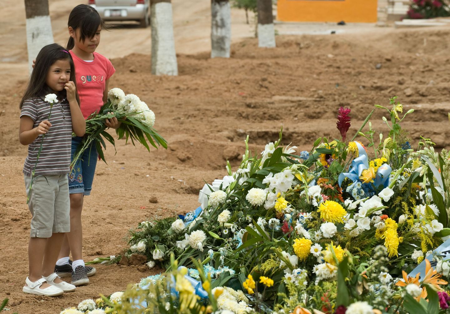 Kaks tüdrukut panevad lilli Hermosillo lasteaiapõlengu ühe ohvri hauale. Kokku hukkus 44 last.