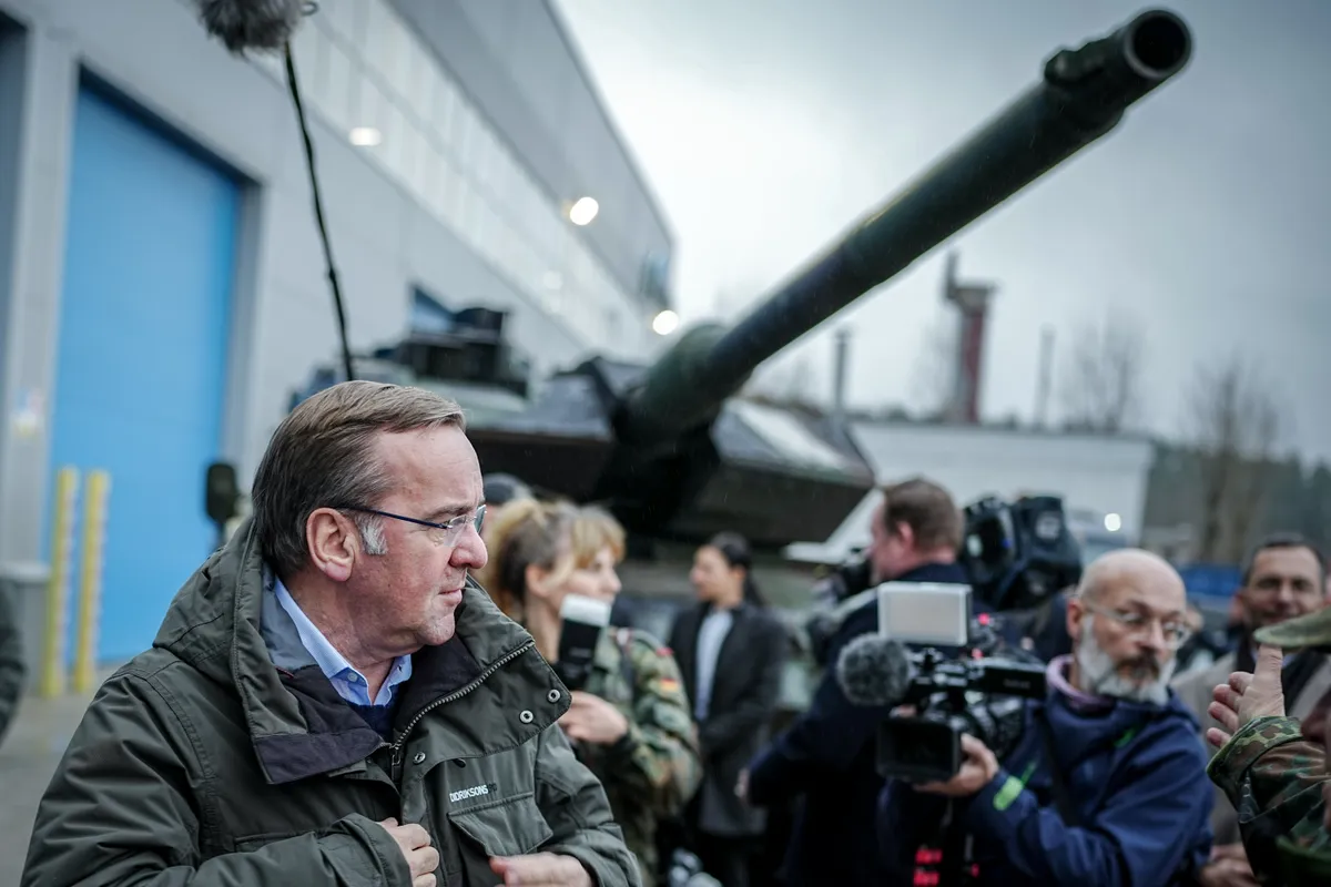 18 December 2023, Lithuania, Jonava: Boris Pistorius (SPD), Federal Minister of Defense, stood in front of a Leopard 2 tank from Ukraine at the Lithuanian Defence Services (LDS) repair hub.