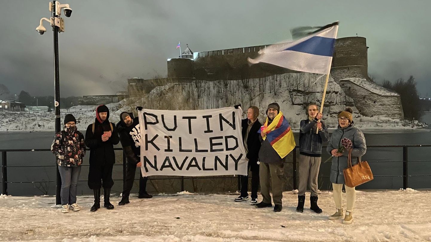 Aleksei Navalnõi mälestuseks korraldatud üritusel osalejad Narva jõe kaldal. Nende käes olev plakat süüdistab Putinit otseselt oma poliitilise vastase mõrvamises.