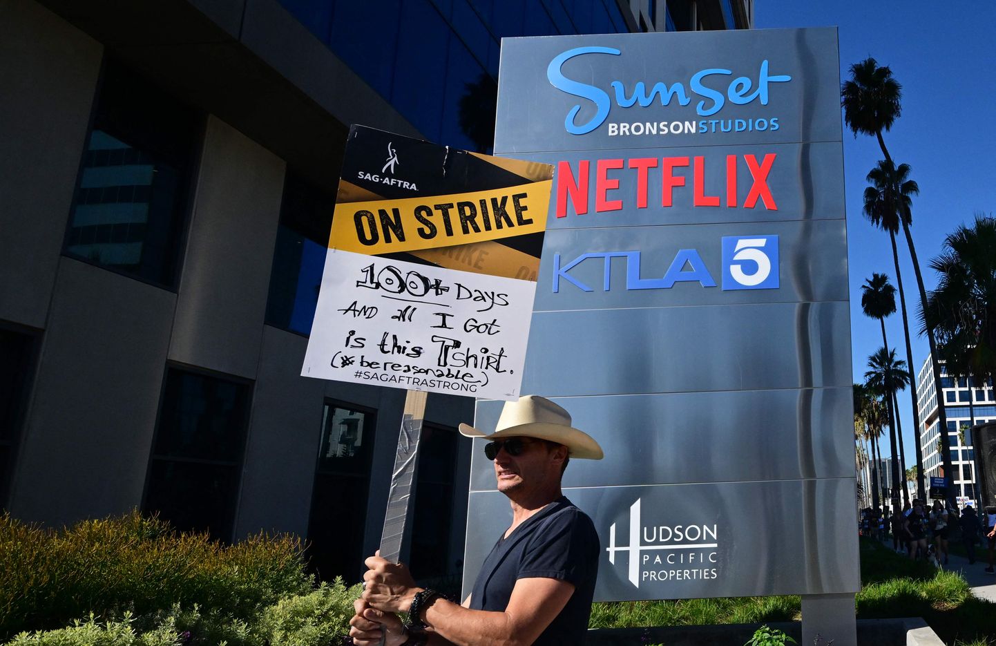 Protestētājs pie "NETFLIX" biroja ēkas Holivudā piedalās mītiņā, kas atzīmē 99 dienu kopš aktieru un scenāristu streika sākuma