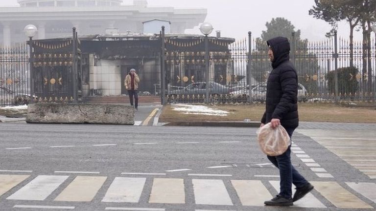 A man walks in front of a the burned out presidential building in Almaty