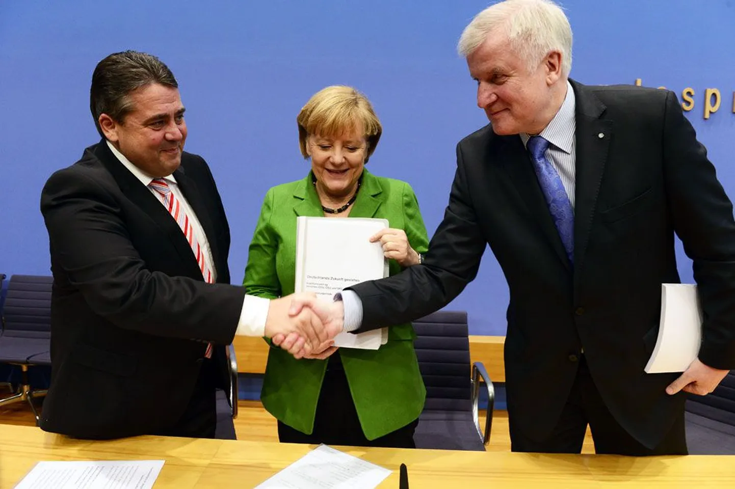 Sotside liider Sigmar Gabriel (vasakul) ja kristlik-sotsiaalse liidu esimees Horst Seehofer suruvad leppe puhul kätt, kantsler Angela Merkel näitab aga 185-leheküljelist võimulepet.