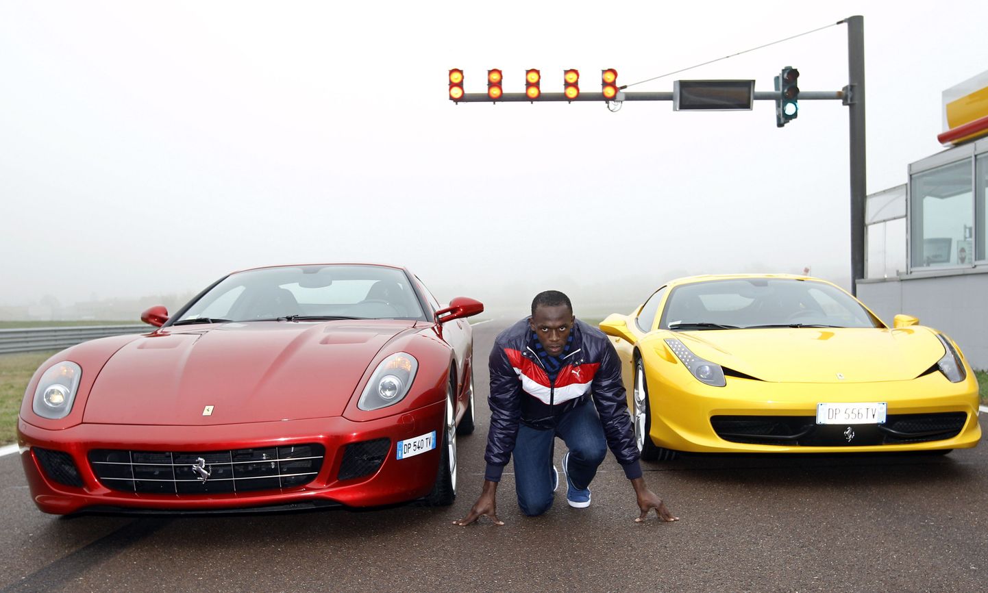 Usain Bolt Ferrari autode kõrval poseerimas.