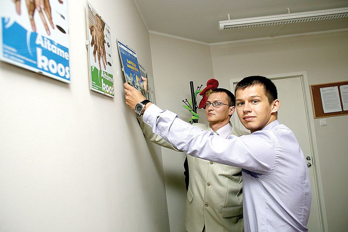 Taavi Lellep (taga) ja Boris Blinov näitavad Tervisekoja kontoris juba toimunud ja tulevaste kampaaniate plakateid.
