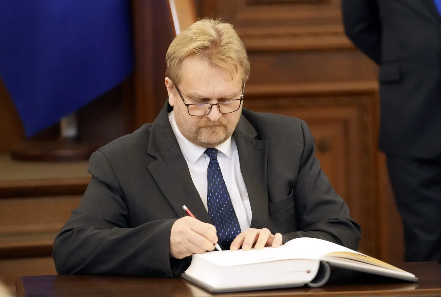 14. Saeimas deputāts Andrejs Ceļapīters zvērestu jeb svinīgo solījumu apliecina ar savu parakstu 14. Saeimas pirmās sēdes laikā.