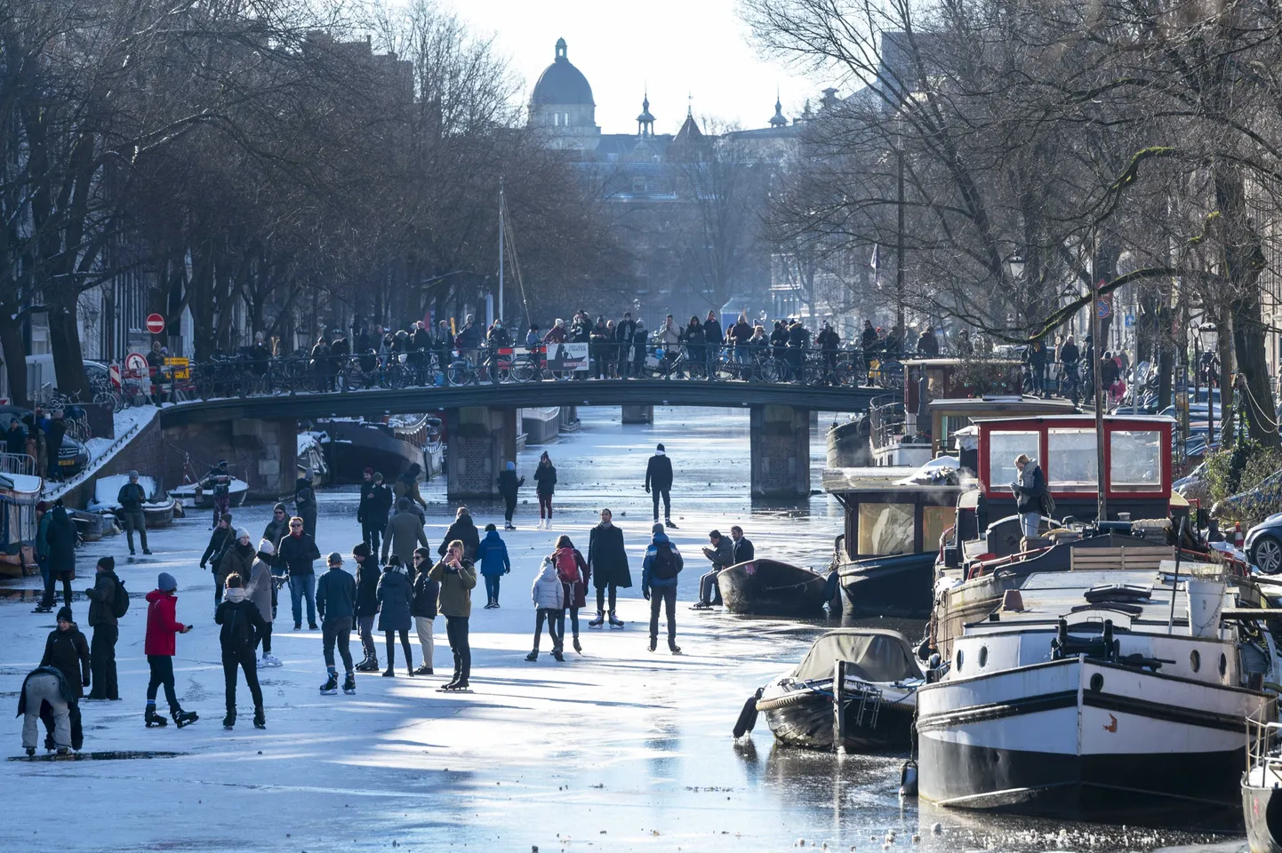 Inimesed jalutamas ja uisutamas Amsterdami kanalil.