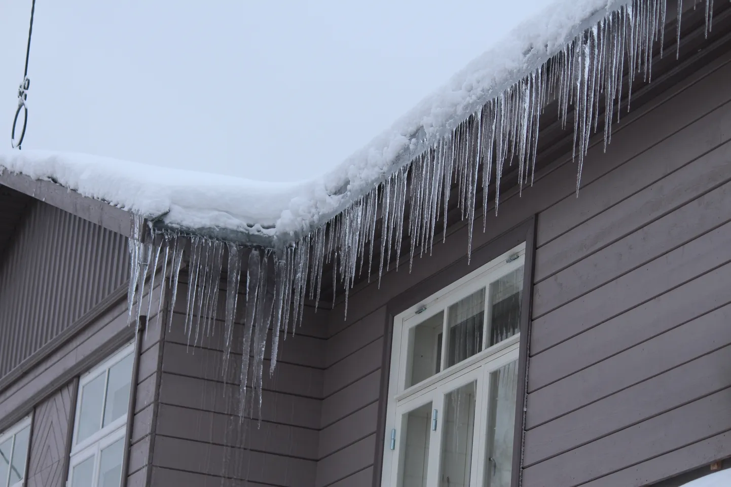 Jääpurikad ja raske lumi ohustavad inimeste elu ja põhjustavad kahju sõidukitele. Fotodel Võru linna katuseräästad.