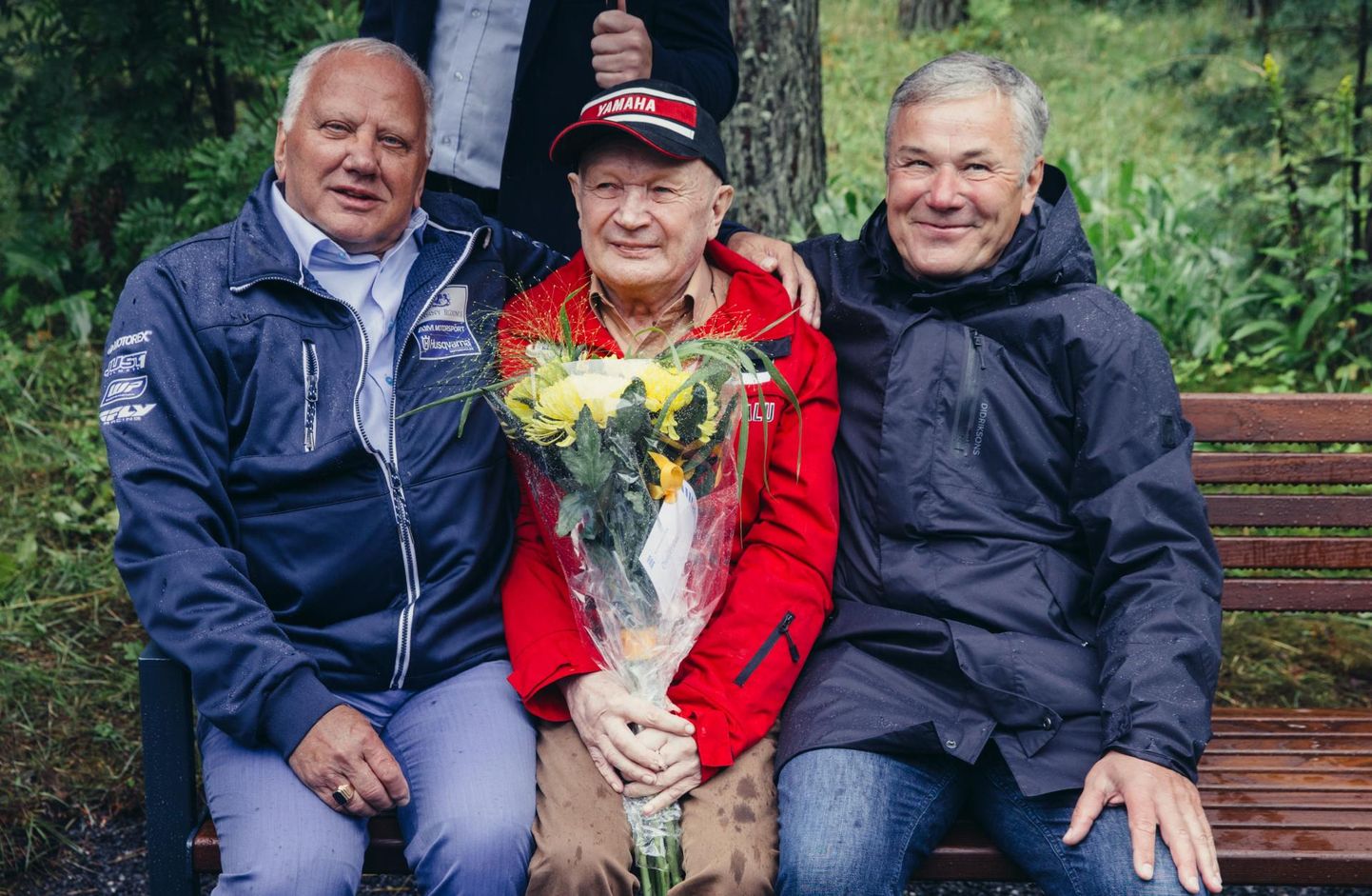 Lembit Teesalu istumas Pirita ringrajale püstitatud endanimelisel mälestuspingil. Tema kõrval on Toivo Asmer (vasakul) ja Jüri Raudsik.