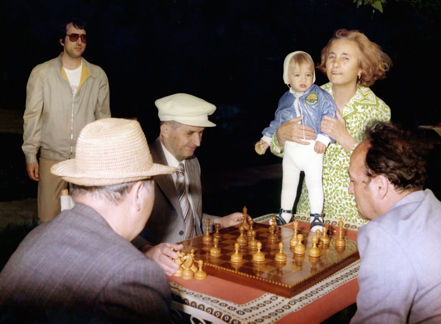 Nicolae Ceauşescu (keskel mütsiga) mängimas malet välisminister Stefan Andreiga. Vasakul on Ceauşescu abikaasa Elena koos poja Valentiniga.