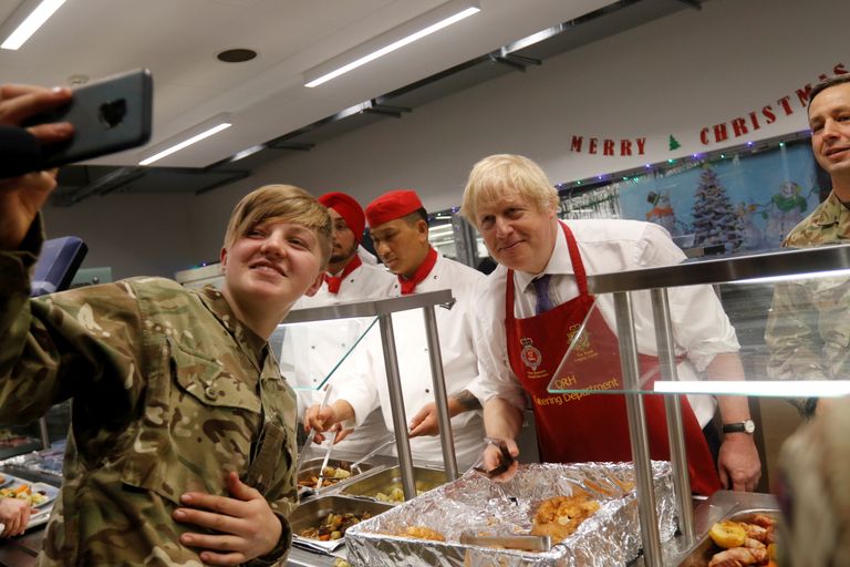 epa08085130 British soldier takes selfie with British Prime Minister Boris Johnson (2-L), during Christmas lunch with British troops at the Tapa military campus in Tapa, Estonia, 21 December 2019. Boris Johnson is on a one-day visit to Estonia and has meeting with British troops from NATO's battle group at Tapa. EPA/VALDA KALNINA
