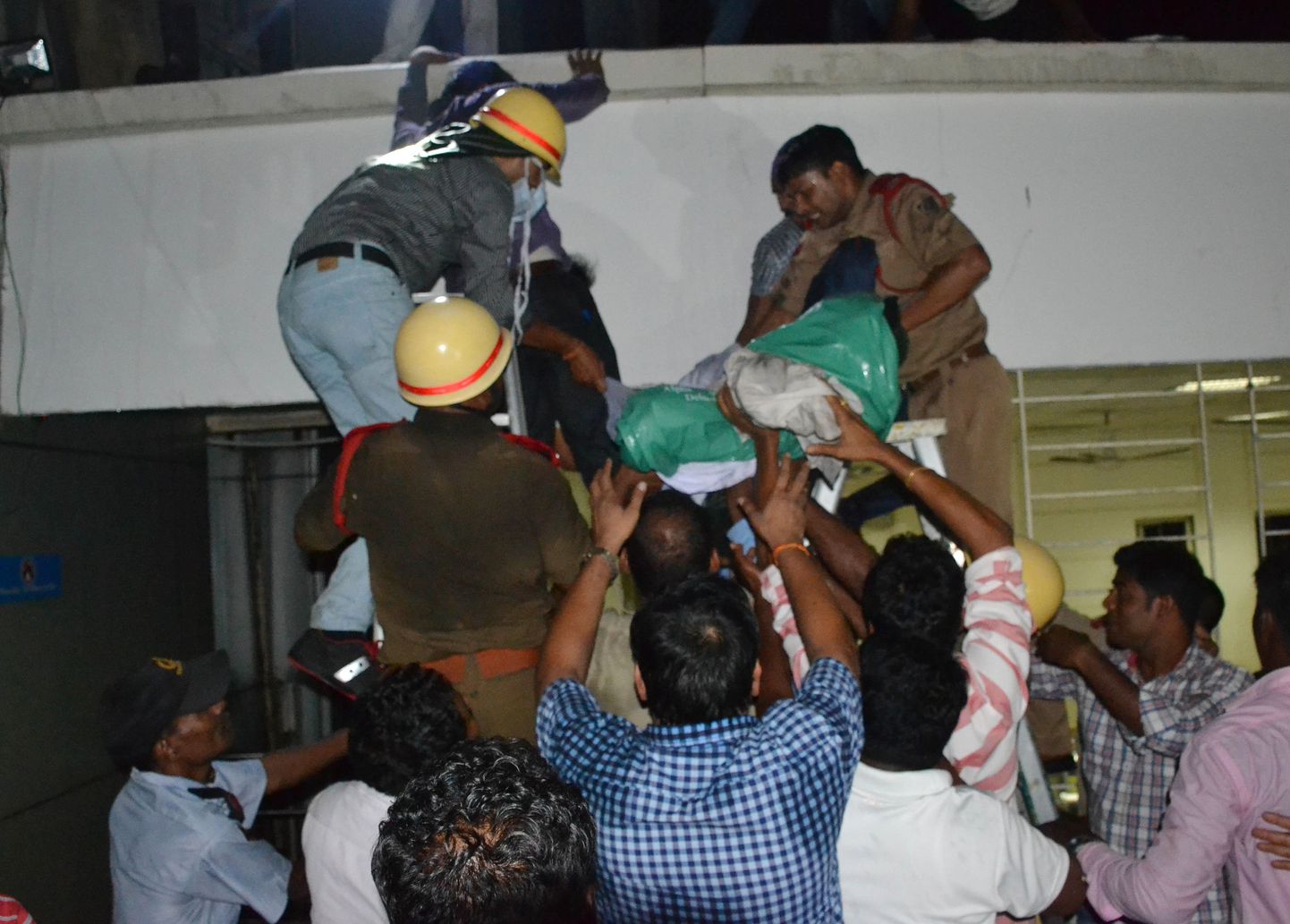 Päästetöötajad ja haigla juurde kogunenud inimesed toovad Bhubaneswari erahaigla põlengust ohvreid välja.