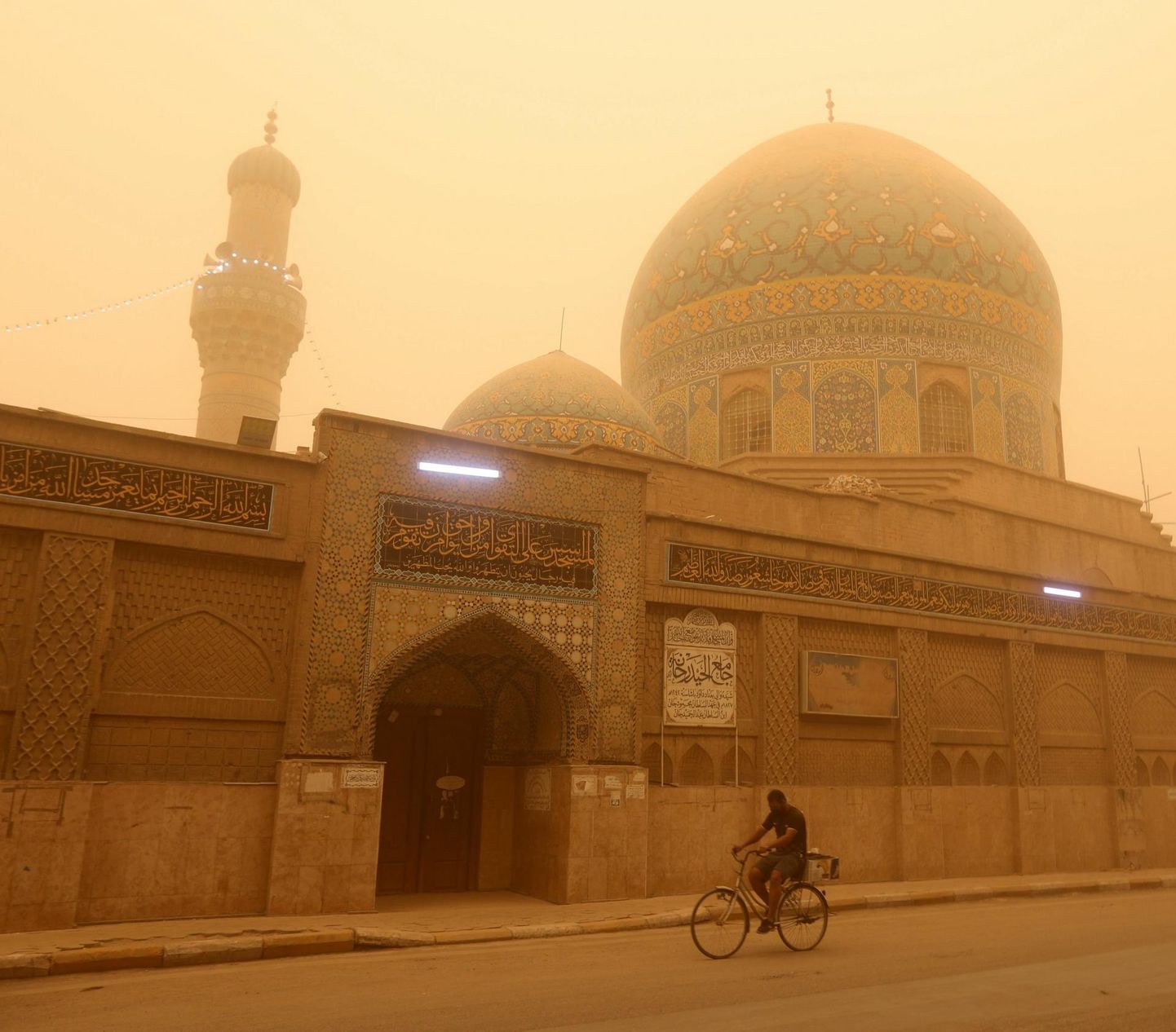 Mees sõidab Bagdadi kesklinnas jalgrattaga mööda Tigrise jõe kaldal asuvast oranžikasse liiva mattunud mošeest.