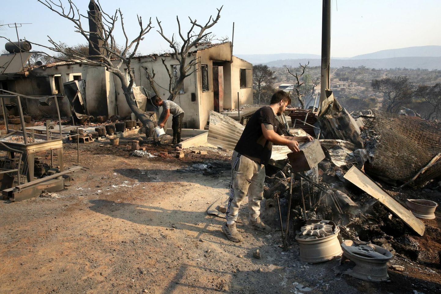 Kohalikud elanikud kallavad Ateenast põhjas Dervenochorias oma põlenud kodu hoovis suitsevale maapinnale vett. 