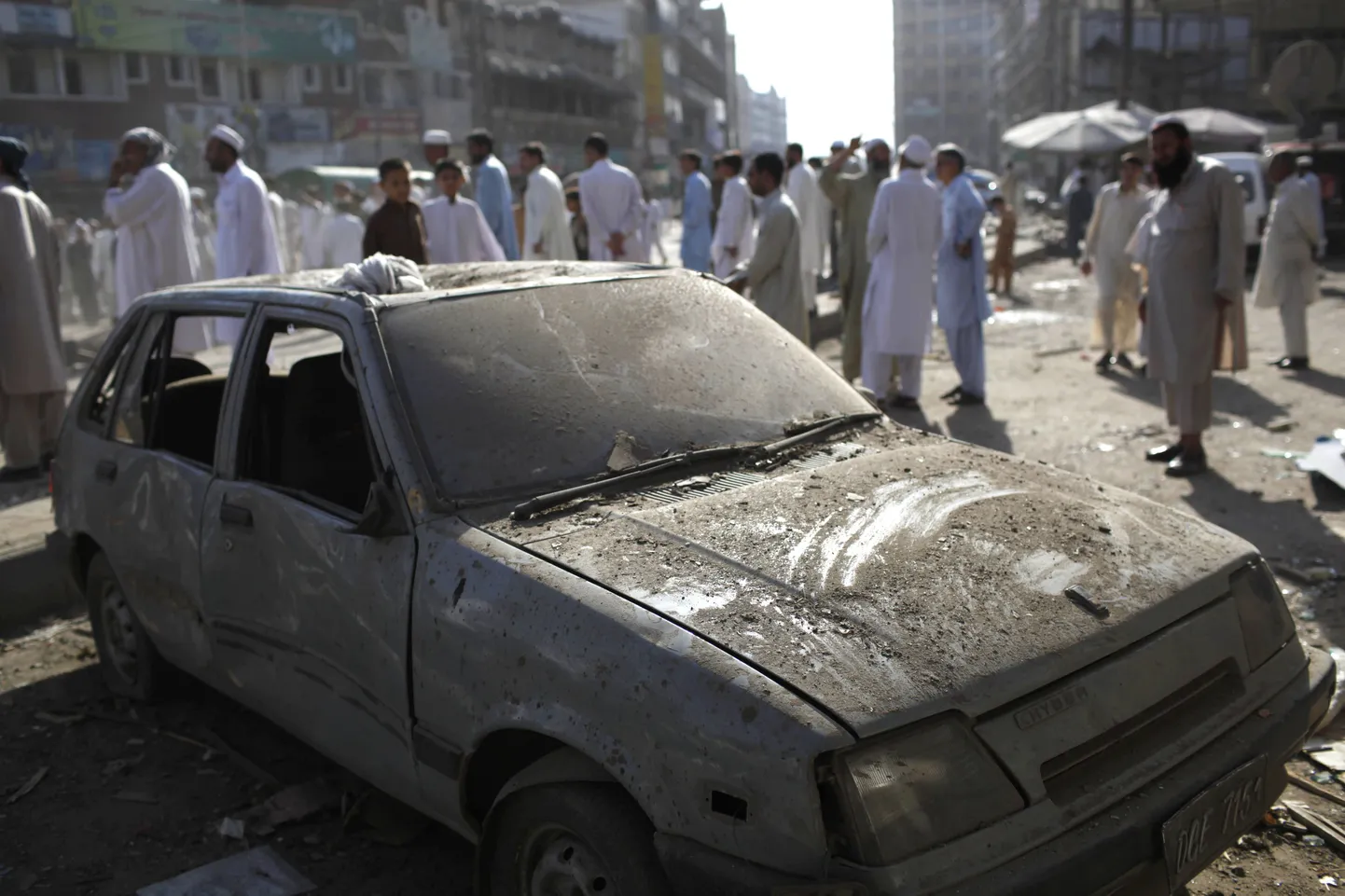 Rahvamass Peshawaris autopommiplahvatuses kahjustusi saanud auto juures.