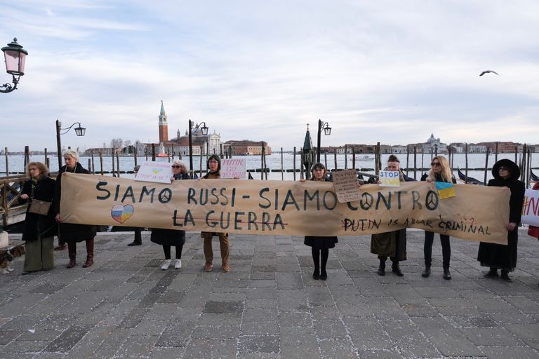 Люди держат лозунг: "Мы русские, мы против войны, Путин военный преступник!", Венеция, 24 февраля 2022 г.