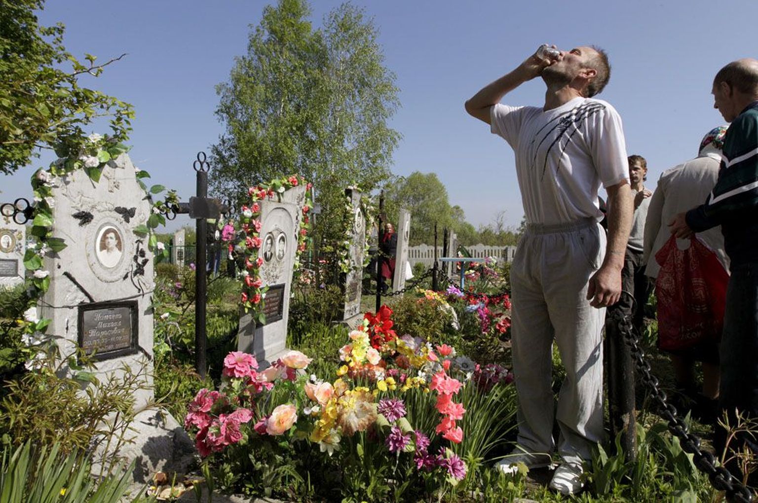 Pildil tähistab Valgevene mees ülestõusmispüha Pogosti küla surnuaial vana kombe kohaselt topsi viinaga.