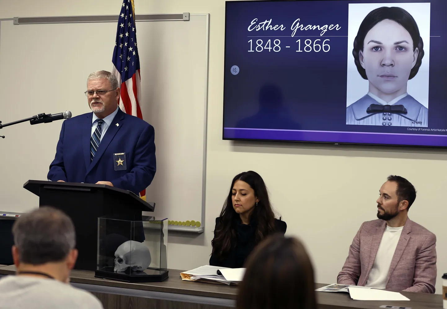 USA Illinois' osariigis asuva Kane'i maakonna koroner Rob Russell selgitab kunstniku joonistuse ees enam kui 150 aastat tagasi surnud Esther Grangerist, kuidas uurijad tuvastasid naise isiku.